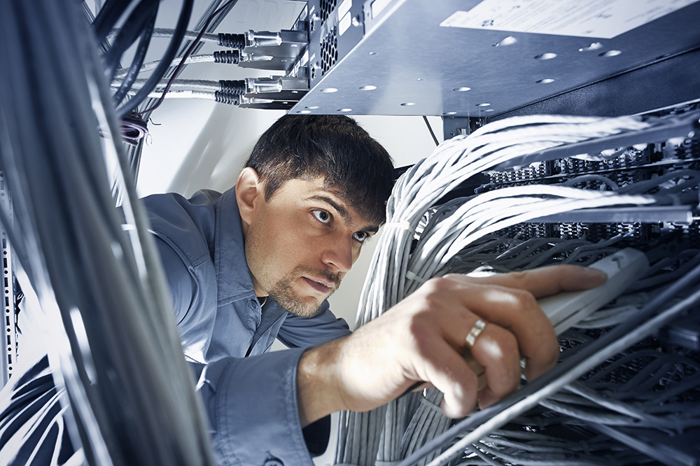 Technician engeneer (30-35) is checking server's wires in data center